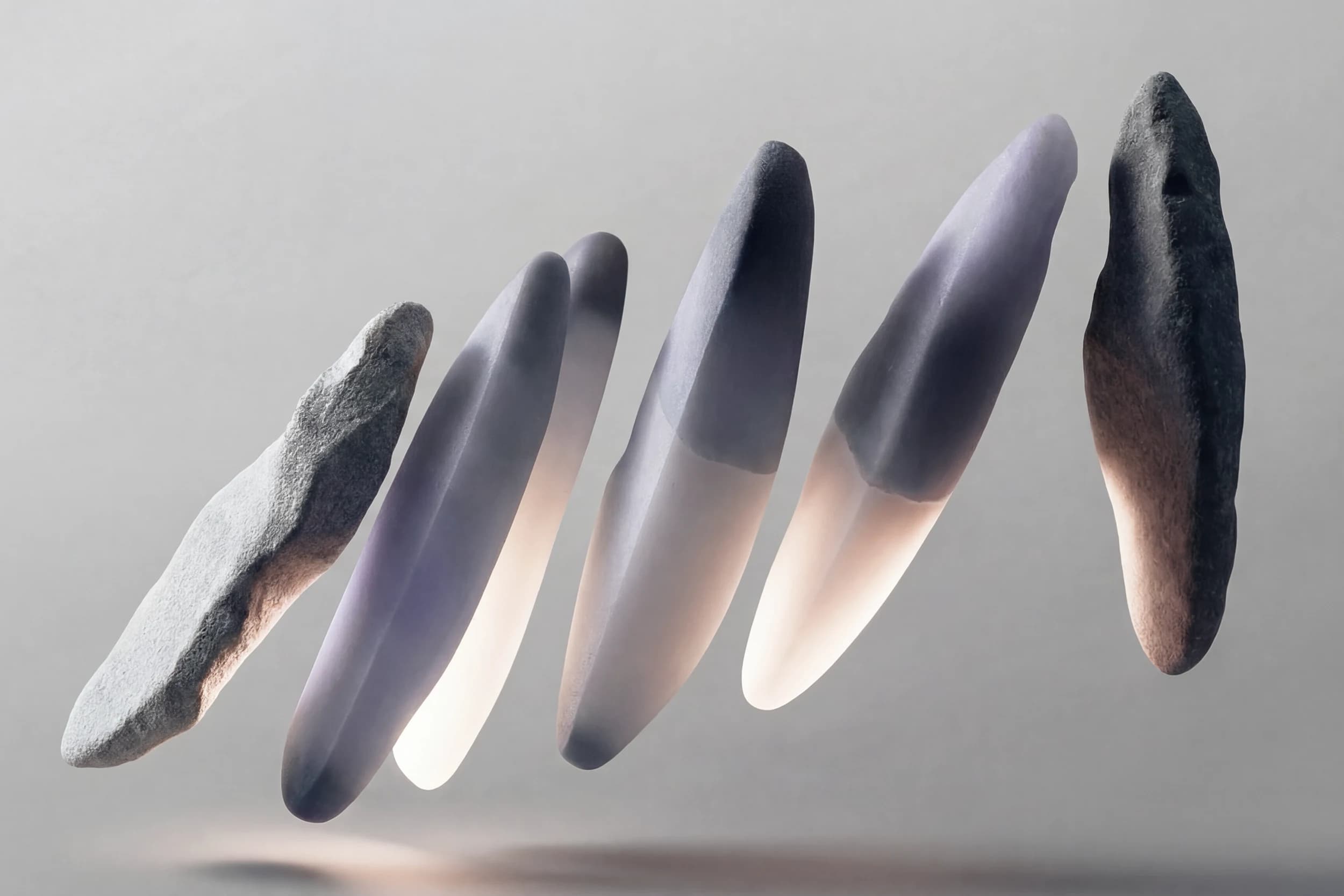 A row of slender stone and frosted-glass forms suspended at an angle over a pale grey ground